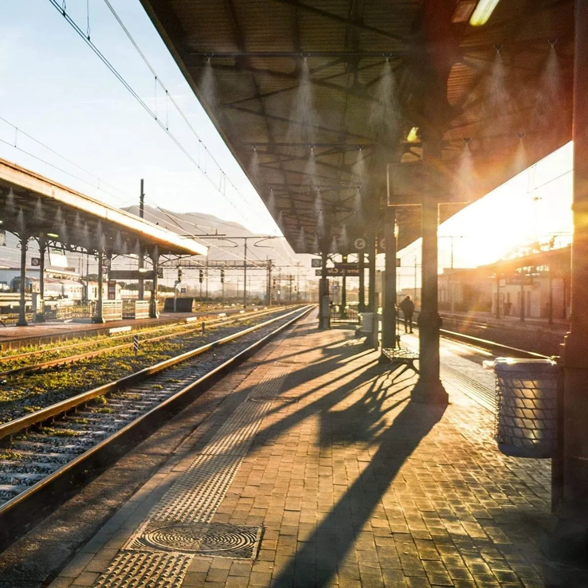 Foggers installed and working in a train station platform with sunlight casting shadows on the ground