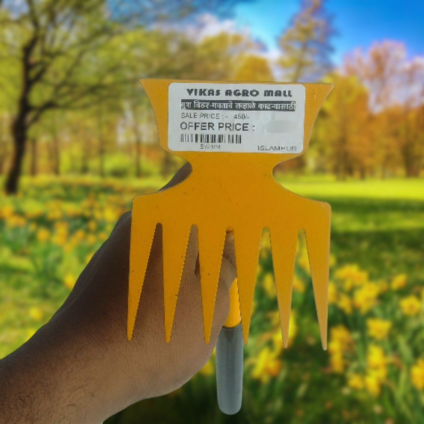 Yellow gardening tool held by a hand with a blurred natural background