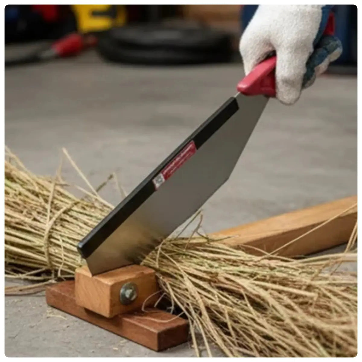 Hand using a sugacane bud cutting machine to cut straw with a blurred background