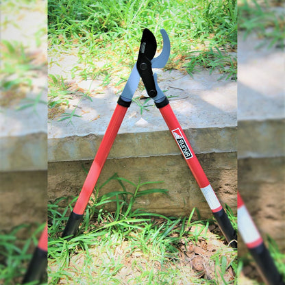Garden pruner with red handle on a grassy ground