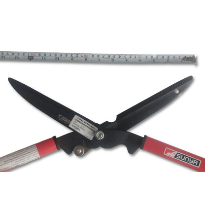 Garden shears with red handles and a ruler for scale on a white background